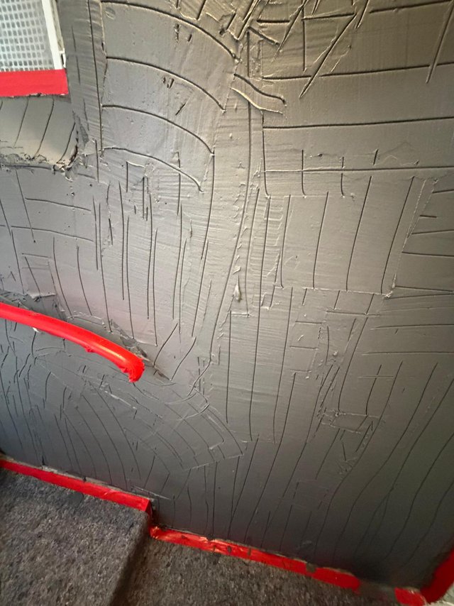 Graue Masse auf Kellerwand mit Kellenstruktur, Nahaufnahme
