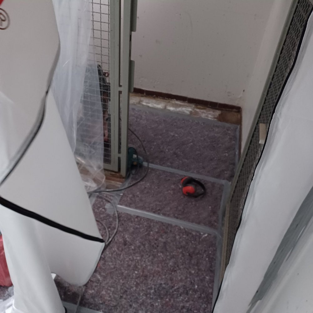 Abgeklebter Durchgang mit Staubschutzfolie, Kabel und Gehörschutz auf Filzabdeckung