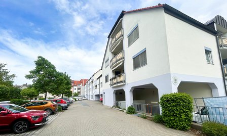 Mehrfamilienhaus mit Balkonen, gepflasterter Zufahrt und parkenden Autos
