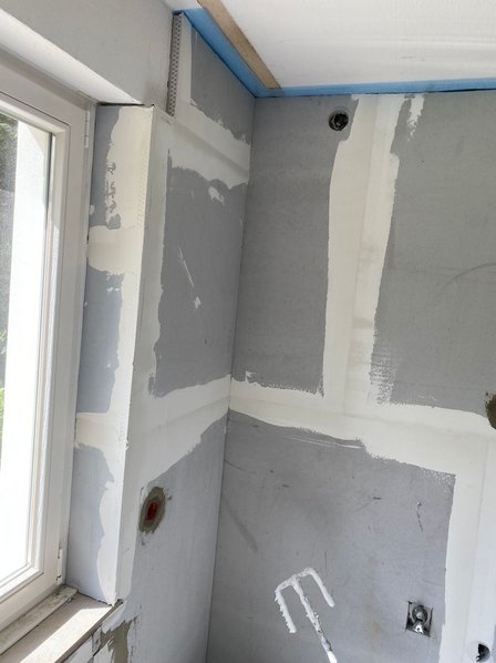 Verspachtelte graue Wandplatten mit sichtbaren Fugen und Öffnungen