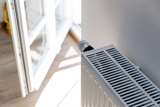 Heizkörper vor offenem Fenster in hellem Raum
