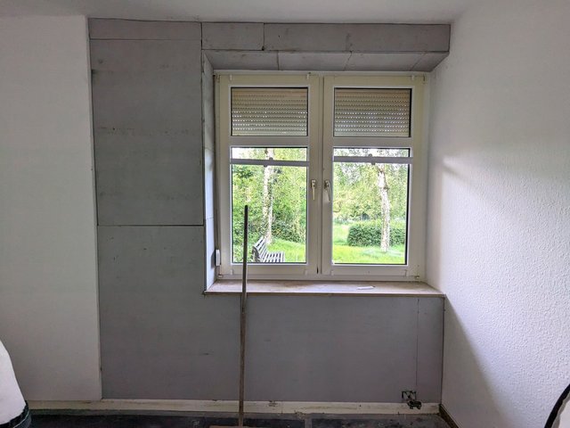 Zwei Fenster in Nische, graue Plattenverkleidung und freiliegender Fensterbankbereich.