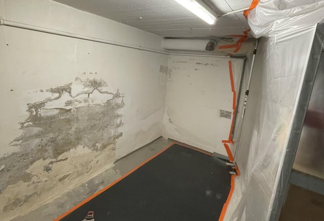 Freigelegte Kellerwand mit Feuchtigkeitsschäden und abgeklebter Schutzfolie