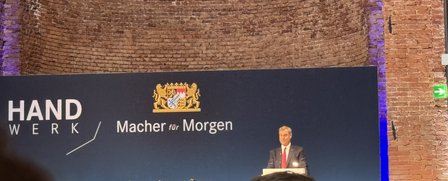 Mann spricht am Rednerpult vor Banner „Handwerk / Macher für Morgen“