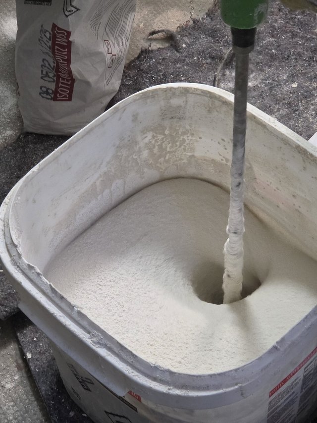 Rührstab mischt weiße Masse in einem Eimer, Nahaufnahme