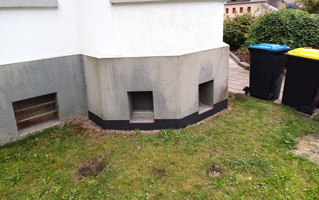 Außenwand mit Lüftungsöffnungen und schwarzem Sockelstreifen