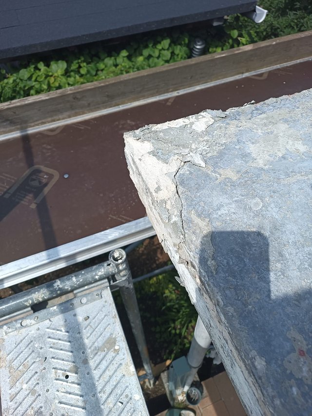 Rissige Betonkante an Balkonbrüstung, Nahaufnahme mit Gerüstplattform