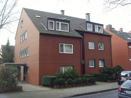 Mehrstöckiges Backsteinhaus mit Satteldach und Dachgauben, Straßenansicht.