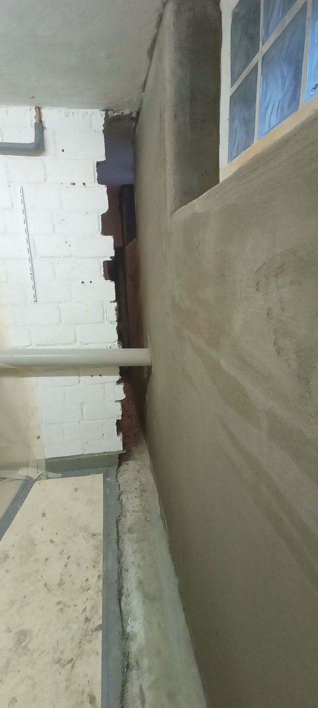 Schmaler Durchgang mit glatter Wand, Rohr und Mauerwerk