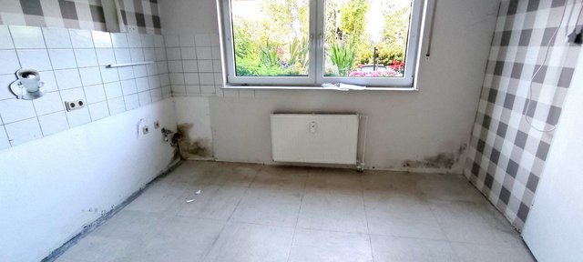 Verschmutzte Zimmerwände mit dunklen Flecken im leeren Raum