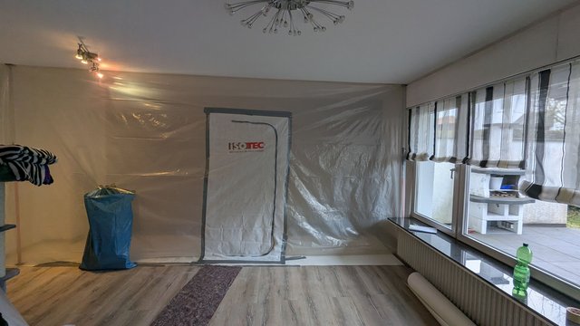 Abgeklebte Staubschutzwand mit ISOTEC-Reißverschlusstür in Zimmer, Fensterfront rechts