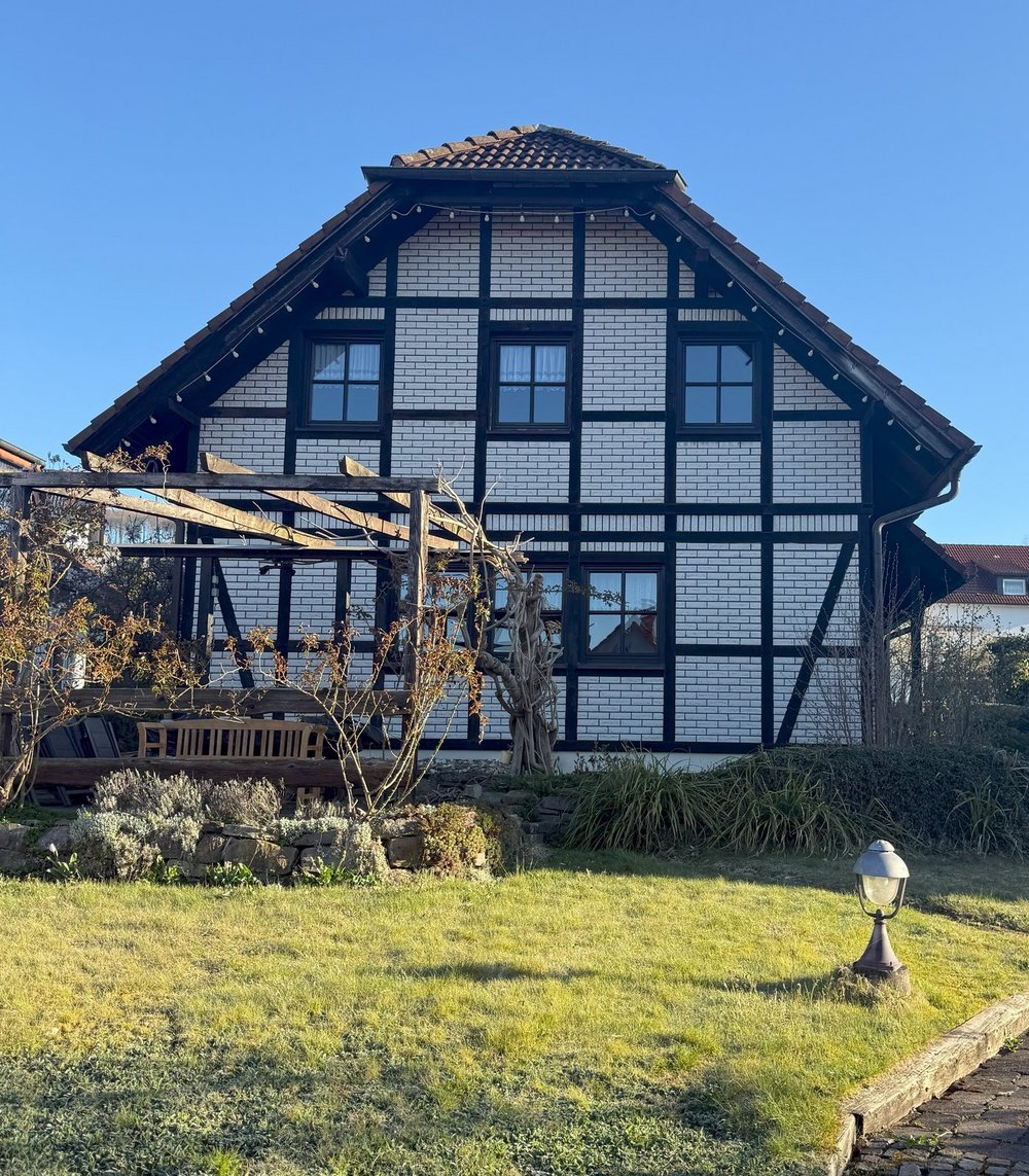 Fachwerkhaus mit weißen Ziegeln und Vorgarten mit grünem Rasen