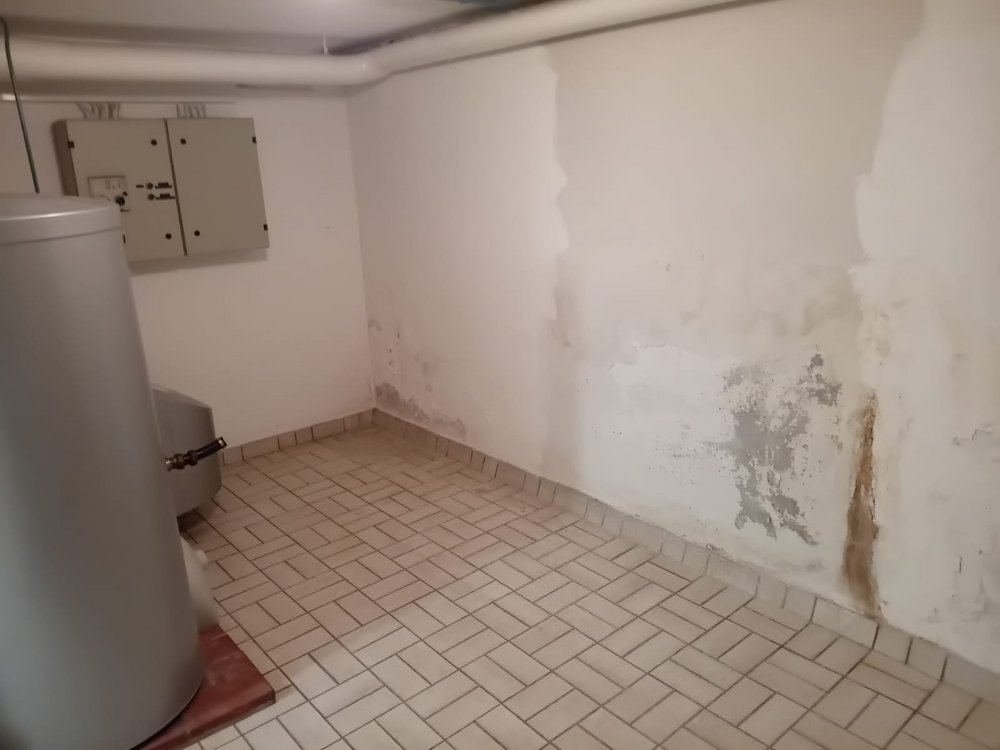 Feuchte Kellerwand mit dunklen Flecken und bräunlicher Ablaufspur