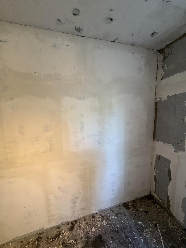 Renovierungsraum mit gespachtelter Wand, Bohrlöchern an der Decke und Bauschutt am Boden