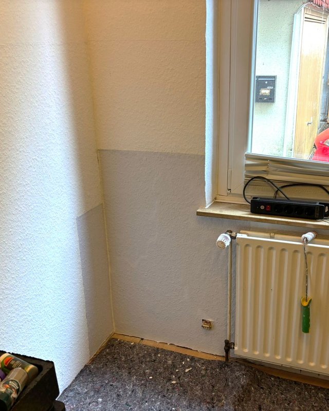 Helle Platte an Wand neben Heizkörper und Fenster im Zimmer