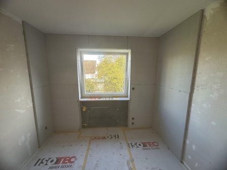 Kleiner Raum mit hellen Platten an Wänden und Boden, Fenster mittig.