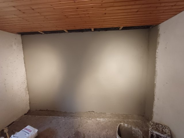 Glatte graue Wand unter Holzdecke mit offenem Spalt am oberen Rand