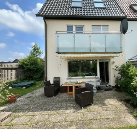 Terrasse mit Sitzmöbeln vor Hausfassade und gelber Markise