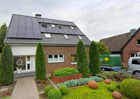 Einfamilienhaus mit Solaranlage auf dunklem Satteldach und gepflegtem Vorgarten