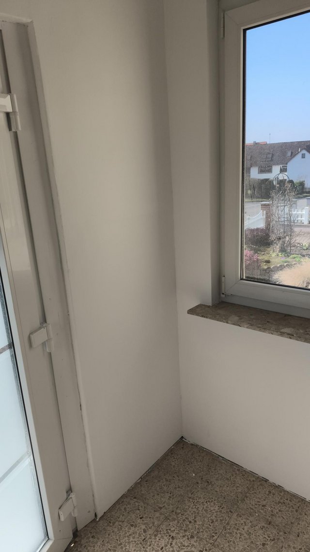 Weiße Zimmerecke mit Fenster, Steinfensterbank und Fliesenboden