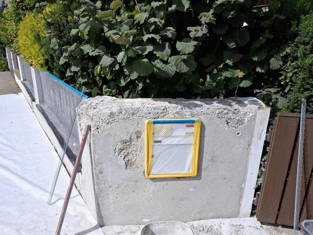 Betonpfeiler mit abgeklebtem Briefkasteneinsatz an Grundstückseinfahrt