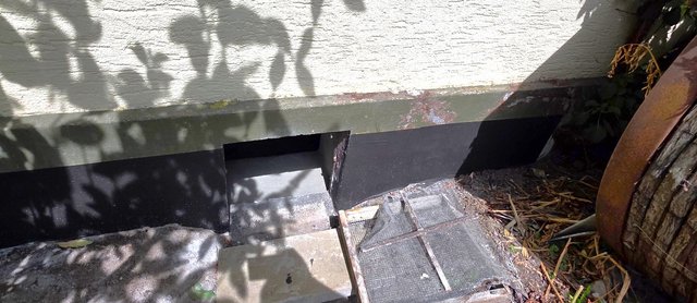 Schwarze Abdichtungsbahn an Sockelbereich, daneben offene Aussparung am Boden.
