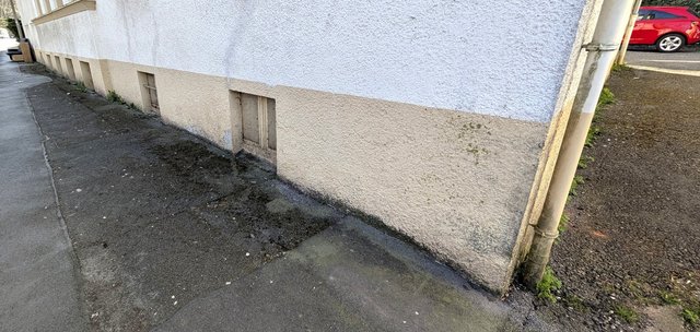 Feuchte Gebäudesockel mit dunklen Verfärbungen an verputzter Fassade