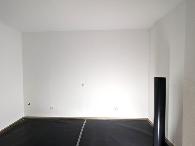 Leerer Raum mit weißer Wand, Steckdosen und schwarzer Rolle im Vordergrund