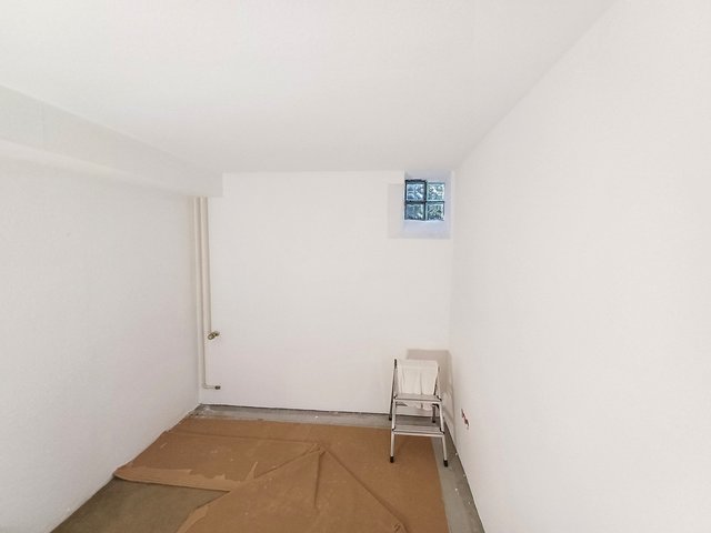 Leerer Raum, Boden mit brauner Papierabdeckung, Trittleiter und Glasbausteinfenster