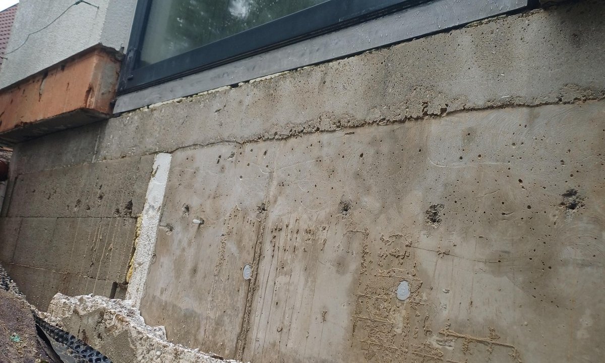 Freigelegte Kellerwand mit Dämmplatte, Noppenbahn und Erdreich am Sockelbereich