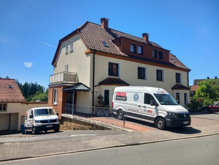 Zwei ISOTEC Fahrzeuge vor Wohnhaus an abschüssiger Straße