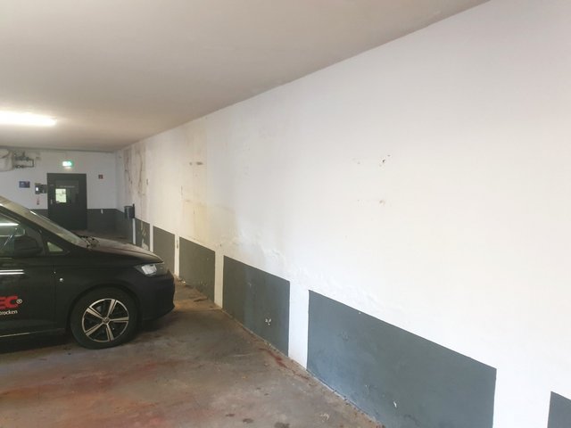 Feuchte Flecken und Verfärbungen an Garagenwand neben geparktem ISOTEC Fahrzeug