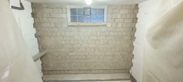 Graue Mauer mit Glasbausteinfenster in schlichtem Kelleraum