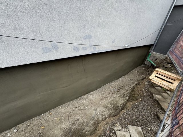 Glatt verstrichene graue Masse auf freigelegter Kellerwand