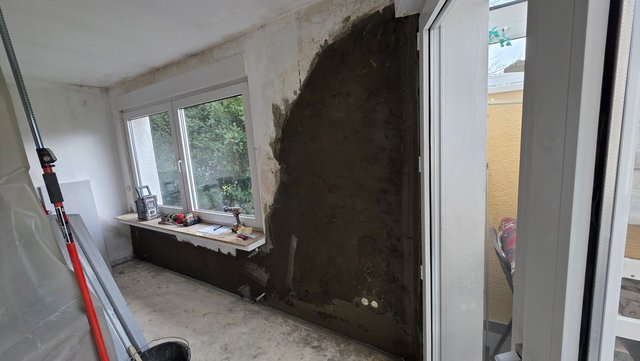 Schwarze Masse auf Wand neben Fenster in renoviertem Zimmer