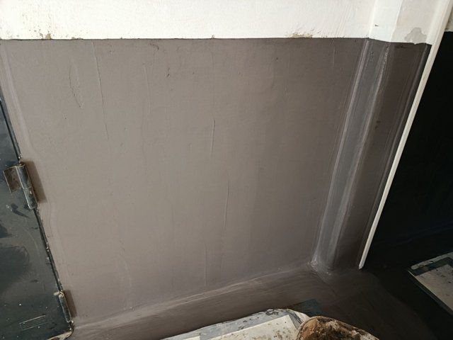 Graue Masse auf Wand und Bodenrand im Türbereich aufgetragen