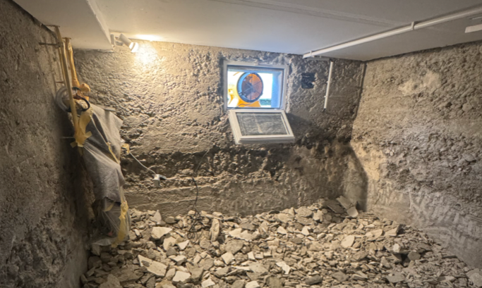 Bauschutt auf Kellerboden, freigelegte Wand unter kleinem Fenster