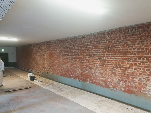 Freigelegte Ziegelwand in Kellerraum mit grauer Masse am Wandfuß