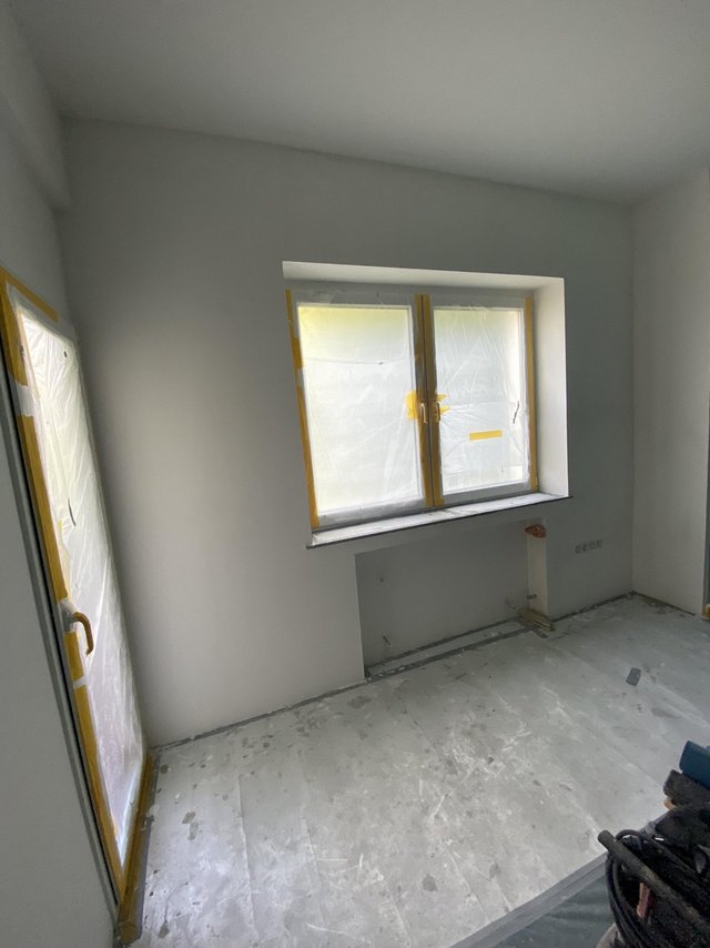 Leerer Raum mit abgeklebt­em Fenster, Tür und staubigem Boden