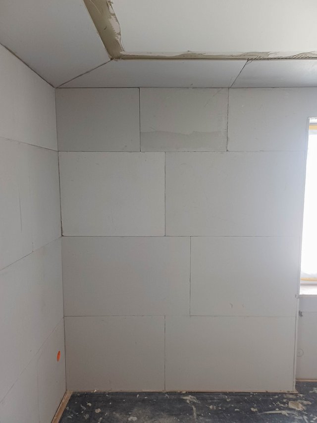 Raumecke mit hellen Platten an Wand und Decke, Fenster rechts