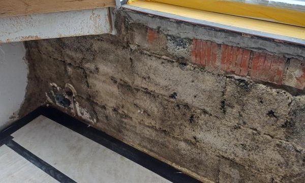 Schimmelbefall und freiliegende Ziegel unter Fensterbank, Innenraum-Ecke