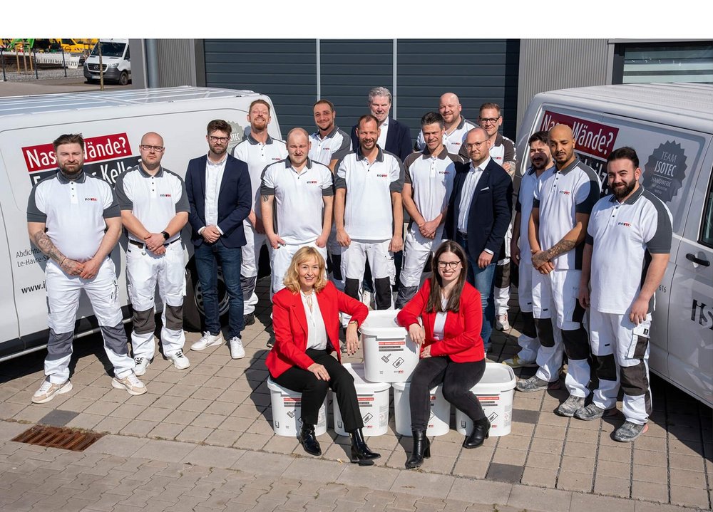 ISOTEC Team posiert draußen vor Firmenfahrzeugen