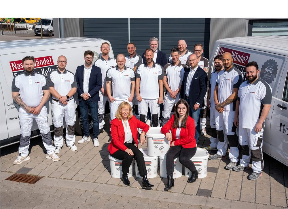 ISOTEC Team posiert draußen vor Firmenfahrzeugen