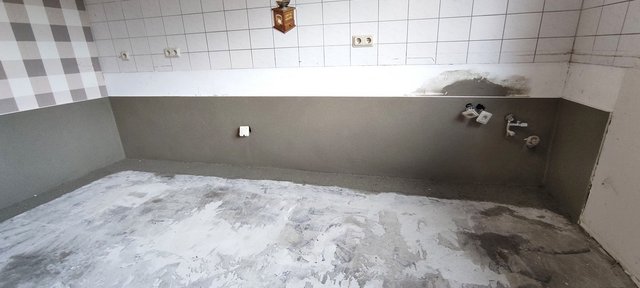 Leerer Raum mit grauer Wandbeschichtung und freiliegenden Anschlüssen.