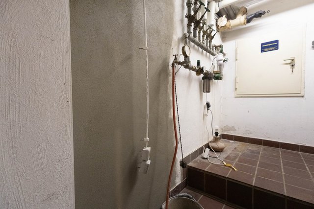 Heizungskeller mit Rohrleitungen, verfärbter Wand und abgeplatzten Stellen am Sockel