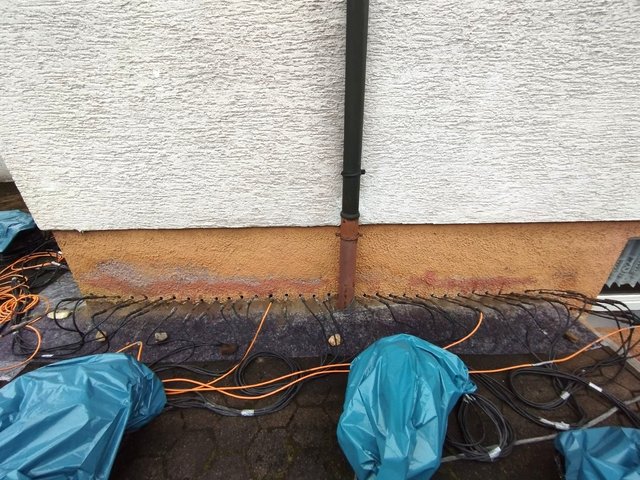 Mehrere Bohrlöcher mit angeschlossenen Leitungen am Gebäudesockel