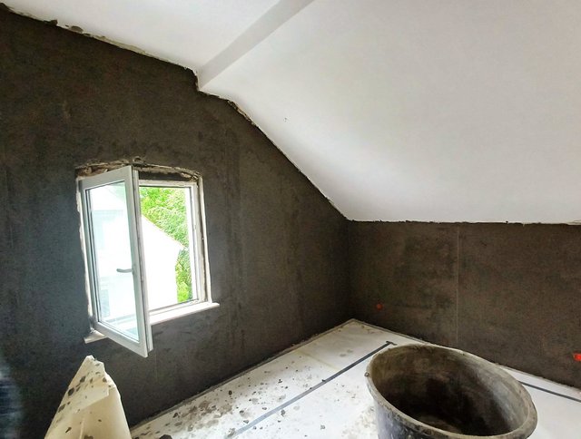 Zimmer mit dunkel beschichteten Wänden, offenem Fenster und großem Behälter