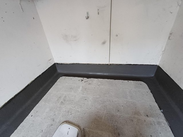 Schwarze Masse am Wand-Boden-Anschluss in leerem Raum