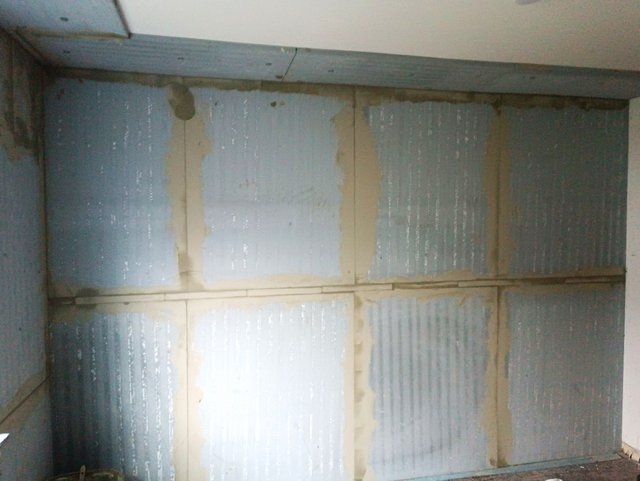 Blaue Dämmplatten mit beigen Fugenstreifen an einer Wand, Nahaufnahme.