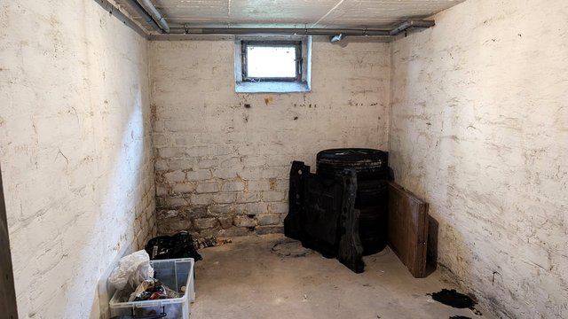 Kellerraum mit verschmutzten Wänden, kleinem Fenster und gelagerten Reifen